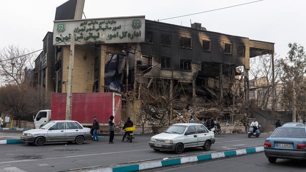 A building heavily damaged by fire as cars drive past