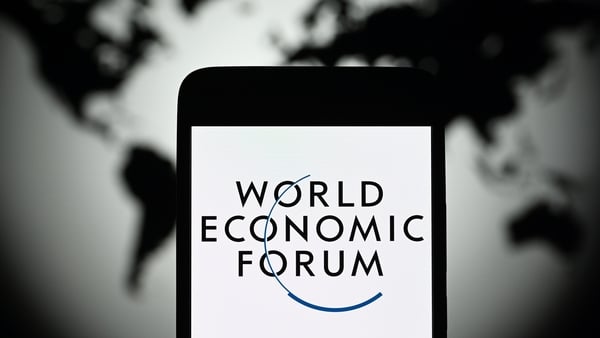World Economic Forum logo seen on a smartphone screen with a map of the world behind it