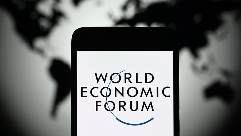 World Economic Forum logo seen on a smartphone screen with a map of the world behind it