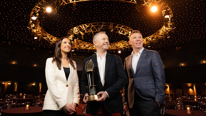 EY representatives, woman in white jacket and man in navy jacket present male winner with award