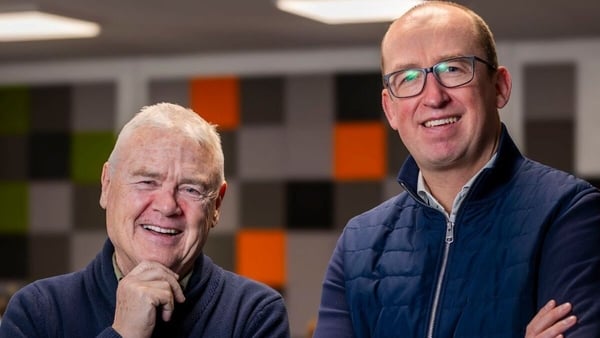 Two smiling business men pose for a photo