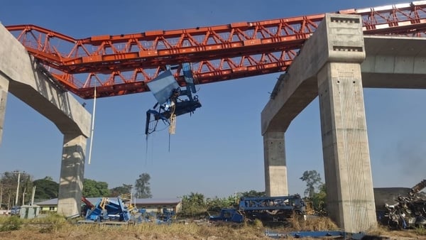 a red crane lies across an overhead rail line under construction