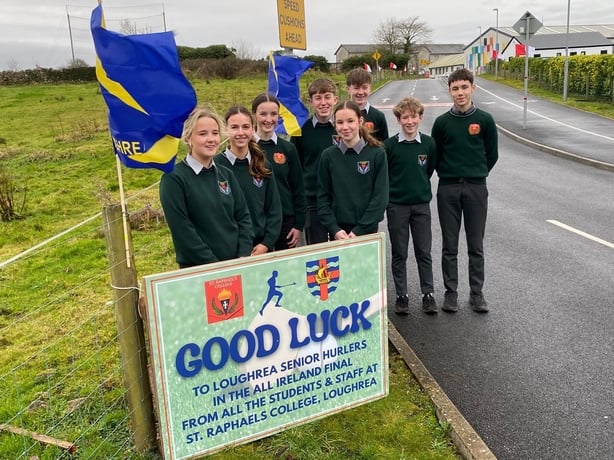 A group of students in school uniforms with a sign reading 'good luck'