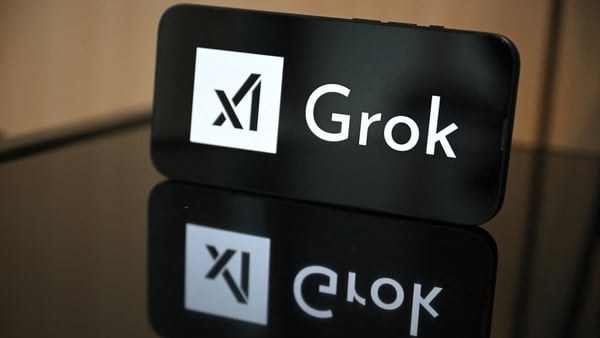This photograph shows a smartphone bearing the logo of Grok