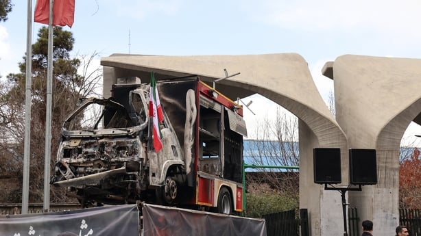 A burnt out fire truck outside a building 