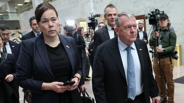 A group of people are seen walking with press cameramen filming