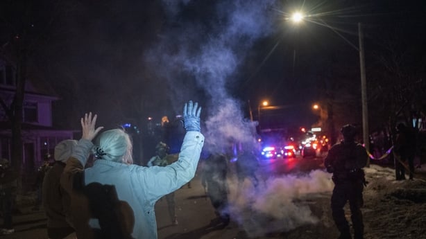 A person holds up their hands as federal law enforcement officers fire tear gas during confrontations with residents