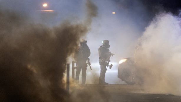 Federal agents standing amid smoke after launching tear gas at residents protesting in Minneapolis