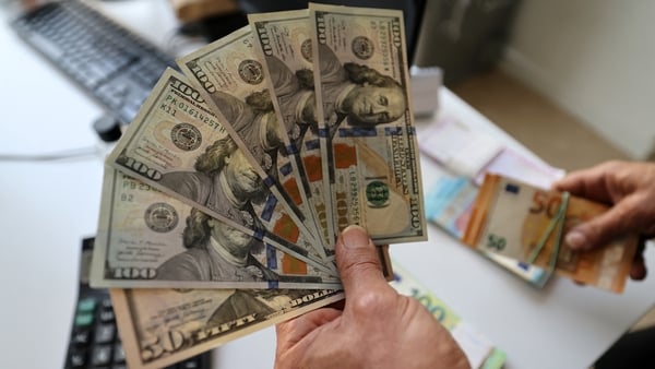 man's hand holds a fan of dollar notes