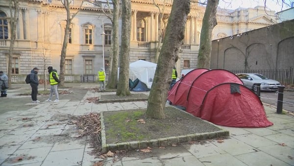 people in hi vis vests seen beside blue and red tents