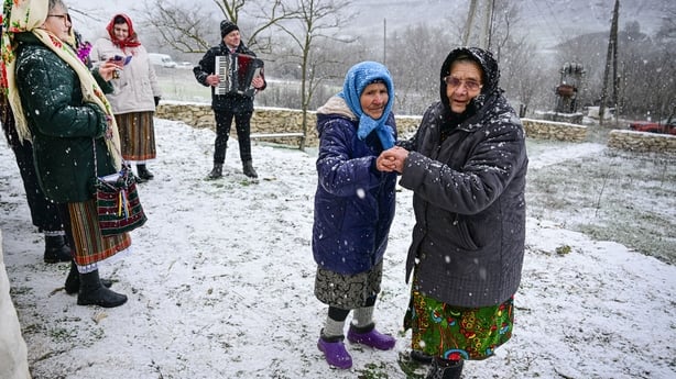 Elderly women wearing winter clothes dance in the snow
