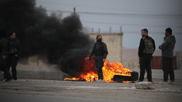 people stand around burning tires