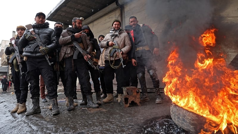 Syrian government troops stand guard next to a burning tyre in the Raqa province on the banks of the Euphrates