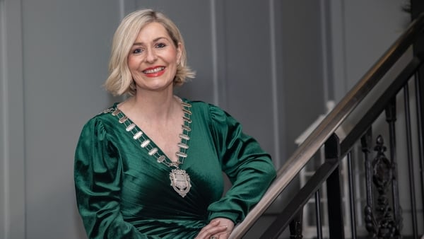 Image of a business woman in a green dress and gold chain