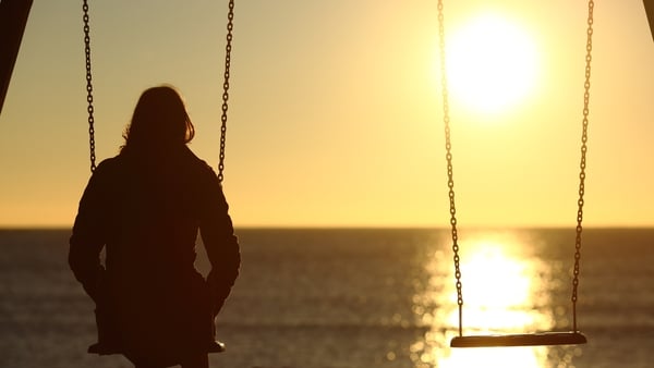 A woman on a swing watching the sunset