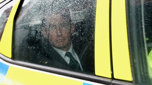 Enoch Burke being escorted by gardaí in a patrol car after appearing in court.