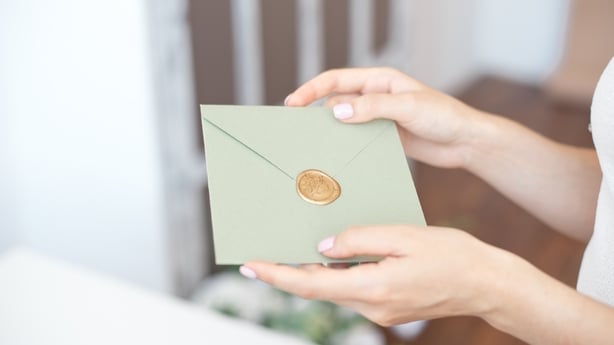 Close-up photo of female hands holding invitation envelope with a wax seal