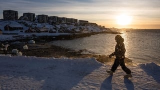 A man walks on the shoreline in Nuuk, Greenland