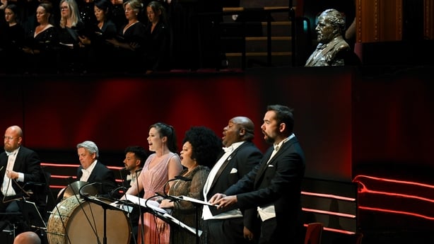 Four soloists perform on stage with a choir behind them and a bust of Beethoven in the background