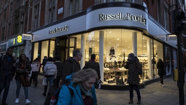 Shoppers walk by the front of a Russell & Bromley shoe shop in London