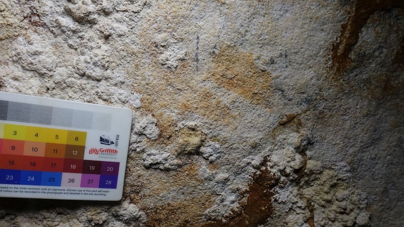 The faint image of a hand stencil that has been dated to 67,800 years ago is seen in a limestone cave called Liang Metanduno on Muna