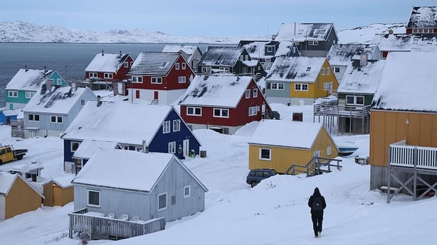 A man walks through the snow towards residential houses in Nuuk