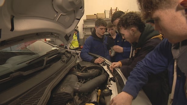 Young men working on a car engine