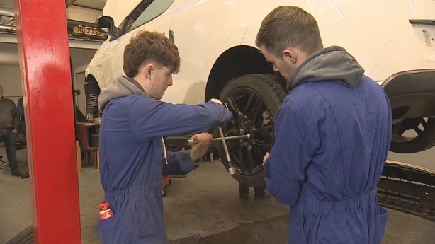 Two young men changing a wheel tyre