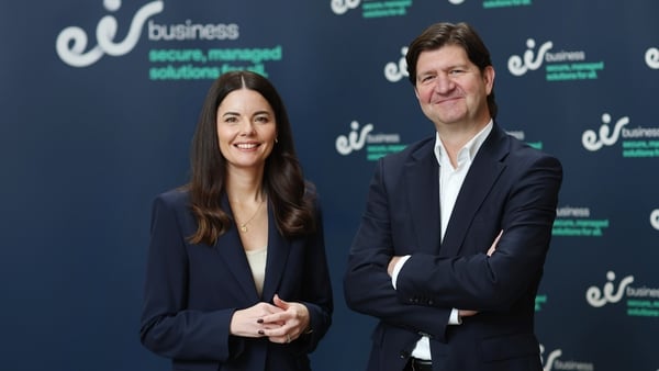 eir's MD and CEO Susan Brady and Oliver Loomes stand with arms folder in front of eir branding