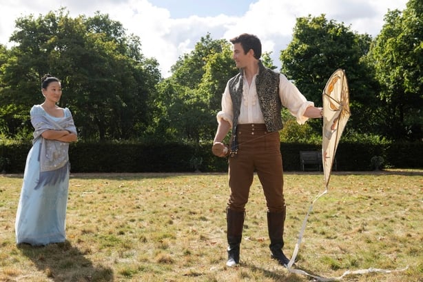 A male and female character speaking outside in a scene from Bridgerton