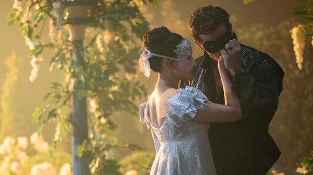 A male and female character at a masquerade ball in a scene from Bridgerton