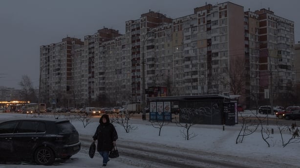 A person walks on sleet covered path past darkened apartment buildings in Kyiv, Ukraine.