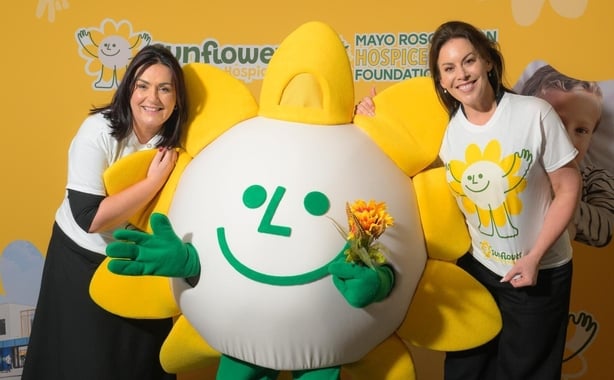 Martina Jennings and Jennifer Carroll MacNeill with a large sunflower mascot