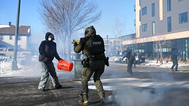 A federal agent points a weapon at a protestor after federal agents allegedly shot a protestor in Minneapolis, Minnesota