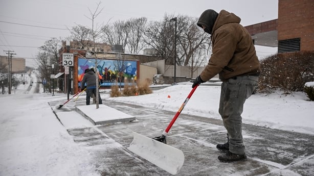 Crews work to clear snow from a footpath 