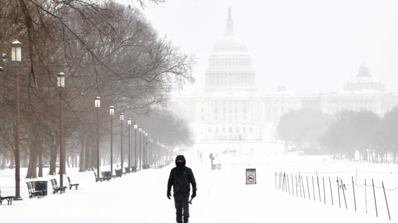 A man walks along the National Mall as snow falls