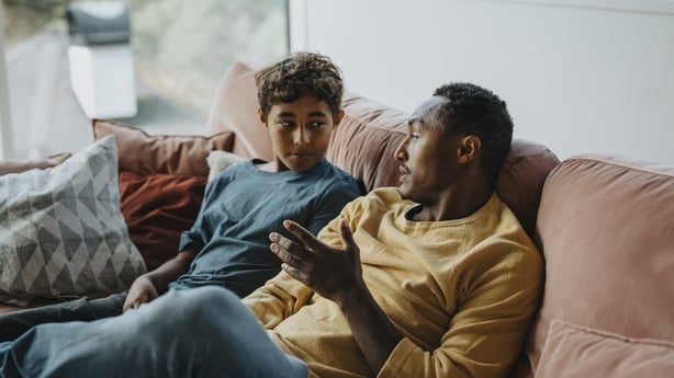 A father talking to his son on the couch