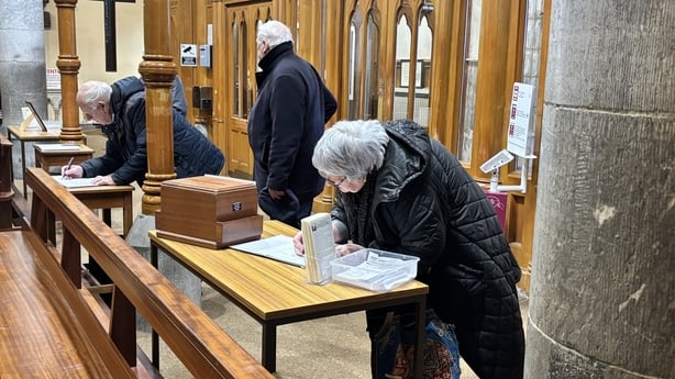 People sign sympathy books inside a church