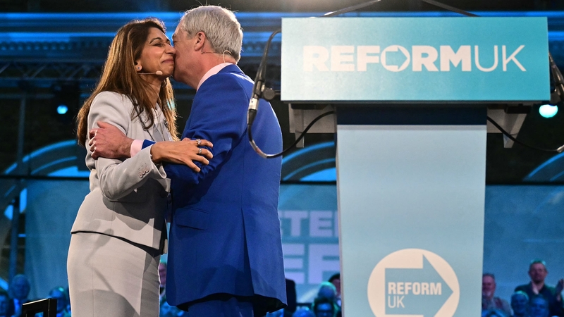 Reform UK leader Nigel Farage hugs Britain's former Conservative party Home Secretary Suella Braverman on stage with a Reform UK podium