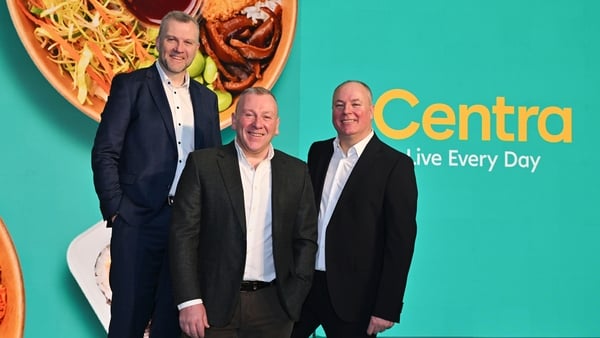 Three business men in suits pose for an image with Centra signage behind them