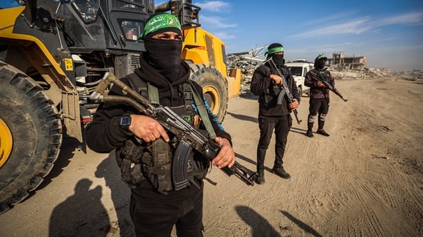 Three Hamas guards stand by a mechanical digger in Gaza 