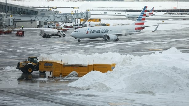 An American Airlines plane behind snow piles at LaGuardia Airport (LGA) in the Queens borough of New York, US, on Monday, Jan. 26, 2026. More than 600 flights scheduled for Monday have been canceled at Newark Liberty International Airport, John F. Kennedy International Airport and LaGuardia Airport,