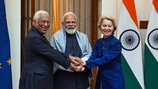 Photo shows two men and a woman clasping hands