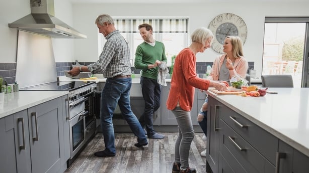 helping their parents to cook a meal in their home while socialising. 