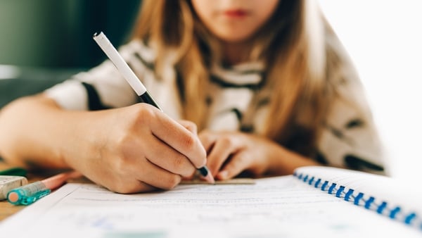 Young girl's hand writing in a school notebook, studying at home