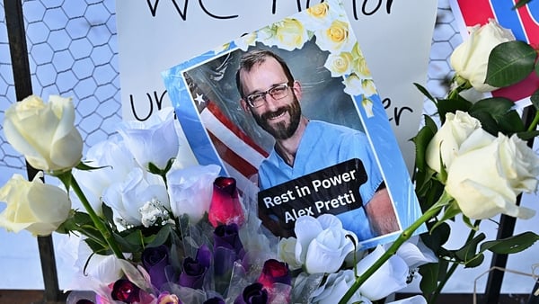 a photo of alex pretti with the words 'rest in power' surrounded by white roses