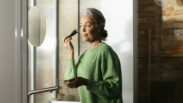 Woman doing make-up with brush at home