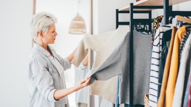 Woman choosing dress in front of mirror.