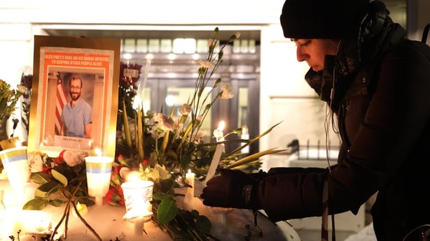 A woman places a candle at a makeshift memorial 