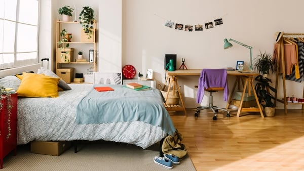 Cozy interior gen z teenager room with bed, workplace, digital devices, plants, photos and some clothes. Home interior room.